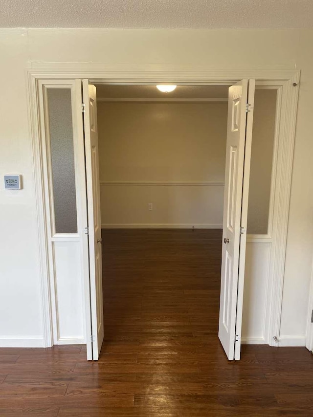 hallway with dark wood finished floors, baseboards, and a textured ceiling