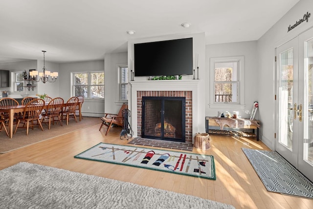 living room with a fireplace, hardwood / wood-style flooring, french doors, and an inviting chandelier