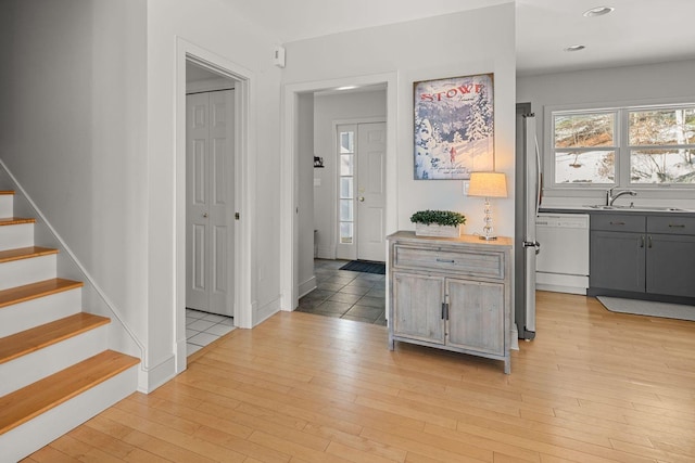 hallway featuring stairs, light wood-style flooring, and a sink