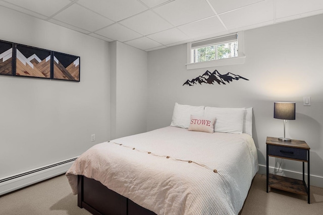 bedroom featuring a baseboard heating unit, carpet flooring, a paneled ceiling, and baseboards