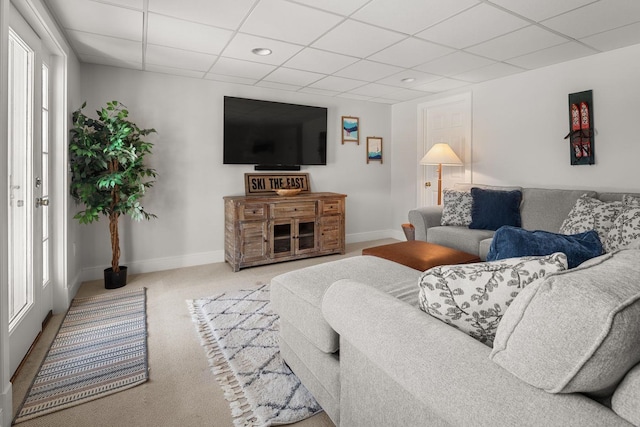 living area with a drop ceiling, carpet floors, and baseboards