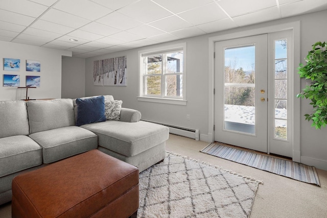 living area featuring a drop ceiling, baseboards, a baseboard heating unit, and carpet