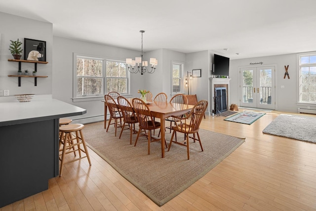 dining space with a fireplace with flush hearth, light wood-style flooring, a baseboard heating unit, and a baseboard radiator