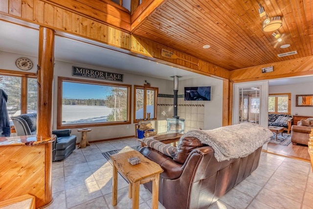 living area with wooden ceiling, a wood stove, and visible vents