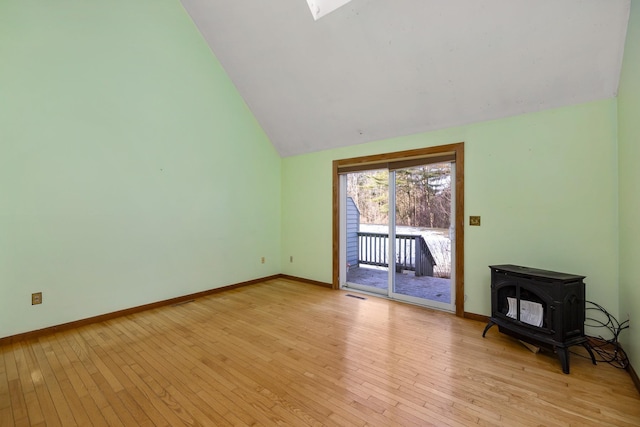 unfurnished living room featuring a wood stove, light wood-style floors, visible vents, and baseboards