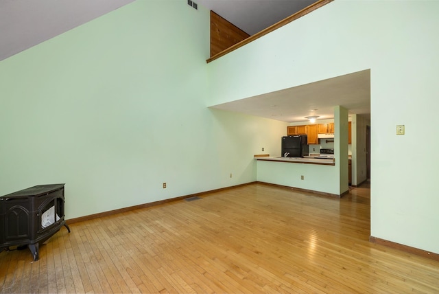 unfurnished living room featuring baseboards, light wood-style floors, and a wood stove