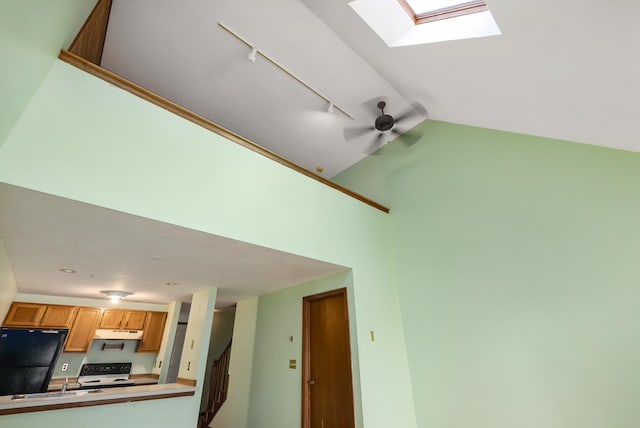 details featuring range with electric cooktop, under cabinet range hood, a skylight, freestanding refrigerator, and a sink