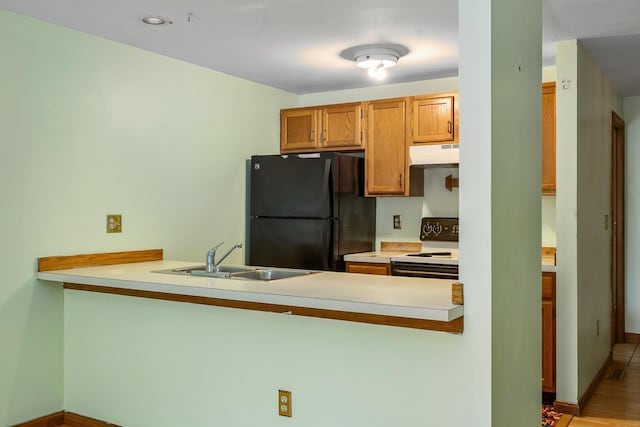 kitchen featuring under cabinet range hood, a peninsula, freestanding refrigerator, and electric range oven