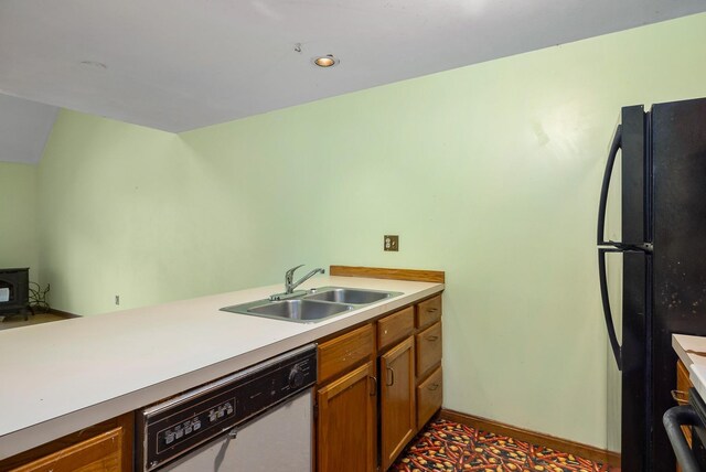 kitchen with brown cabinetry, freestanding refrigerator, a sink, light countertops, and dishwasher