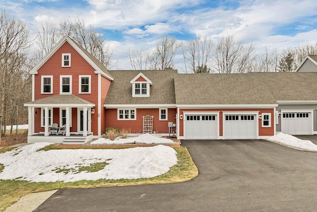 view of front of house featuring an attached garage, a porch, driveway, and a shingled roof