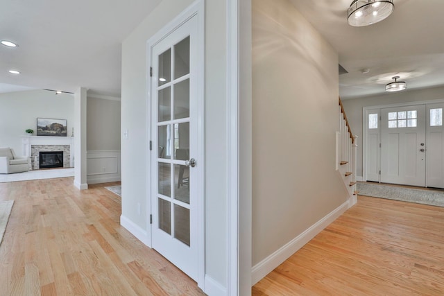 entrance foyer featuring recessed lighting, stairway, a stone fireplace, light wood finished floors, and baseboards