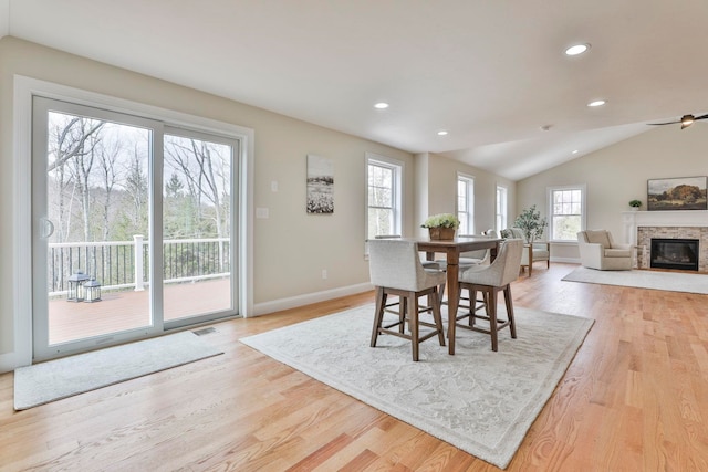 dining room featuring recessed lighting, light wood-type flooring, lofted ceiling, and a fireplace