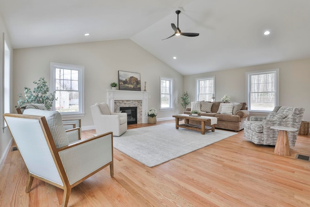 living area with a fireplace with flush hearth, a healthy amount of sunlight, and wood finished floors