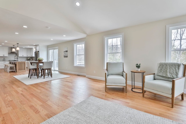 living area featuring light wood-style flooring, recessed lighting, a healthy amount of sunlight, and baseboards