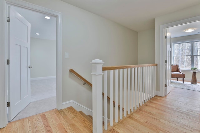 corridor with an upstairs landing, recessed lighting, baseboards, and wood finished floors