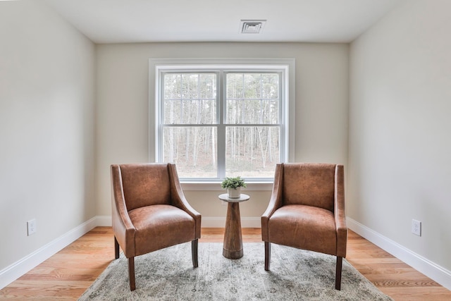 living area with visible vents, baseboards, and wood finished floors