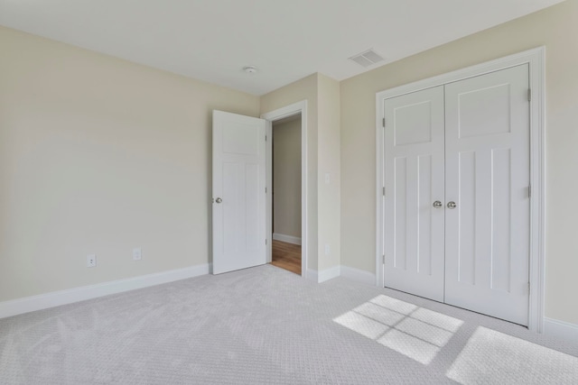 unfurnished bedroom with visible vents, baseboards, a closet, and carpet flooring