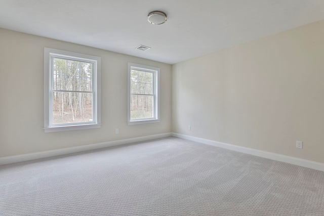 unfurnished room with baseboards, visible vents, and light carpet