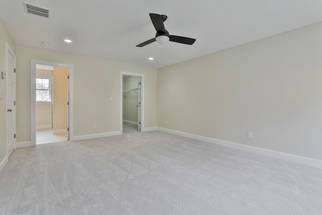 unfurnished bedroom featuring a spacious closet, visible vents, baseboards, light colored carpet, and recessed lighting