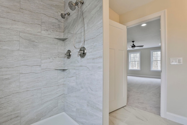 bathroom with marble finish floor, tiled shower, and baseboards