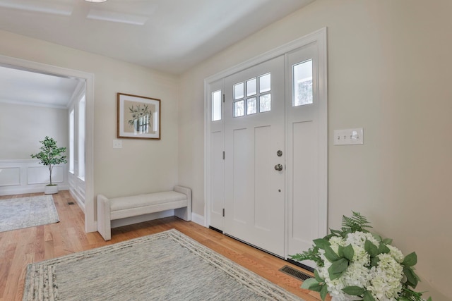 foyer entrance with light wood-type flooring, visible vents, and a decorative wall