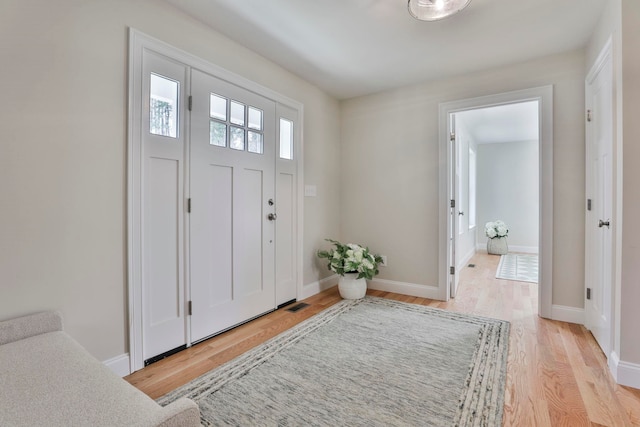 foyer entrance featuring light wood-style flooring, visible vents, and baseboards