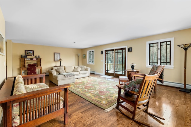 living area with a baseboard heating unit, baseboards, and wood finished floors