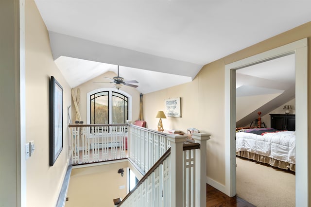 corridor with carpet, lofted ceiling, an upstairs landing, and baseboards