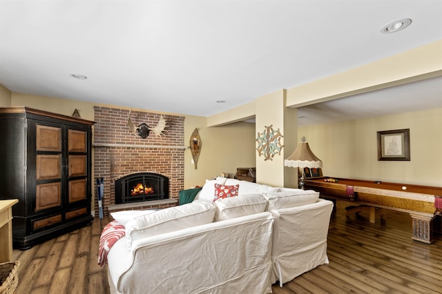 living room featuring a brick fireplace and wood finished floors