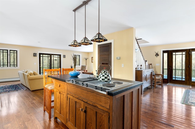 kitchen featuring dark countertops, open floor plan, stainless steel electric cooktop, and dark wood-type flooring