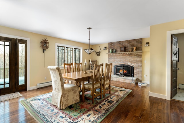 dining area featuring a baseboard heating unit, wood finished floors, baseboards, and a fireplace