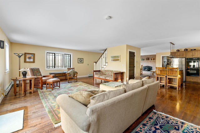 living area featuring stairway, wood finished floors, baseboards, and a baseboard radiator