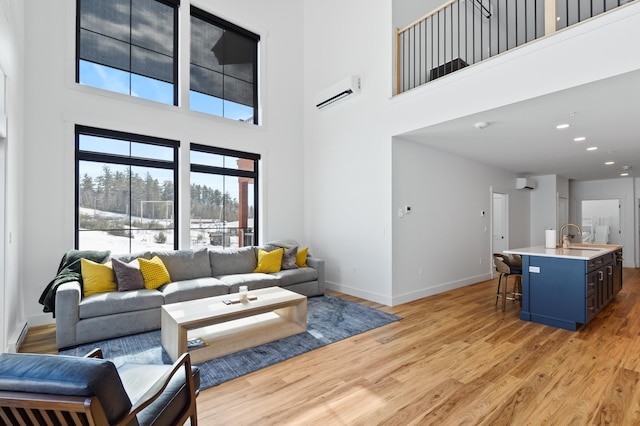 living room featuring light wood finished floors, recessed lighting, baseboards, and a wall unit AC