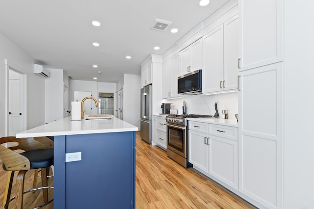 kitchen featuring visible vents, an island with sink, a sink, a breakfast bar area, and high end appliances