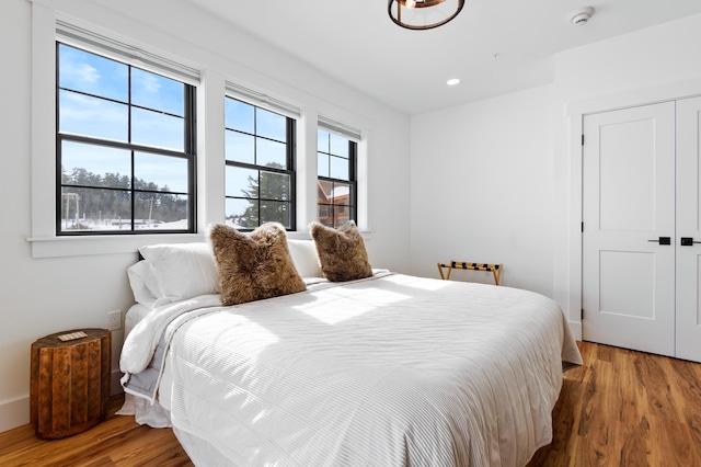 bedroom with a closet, recessed lighting, multiple windows, and wood finished floors