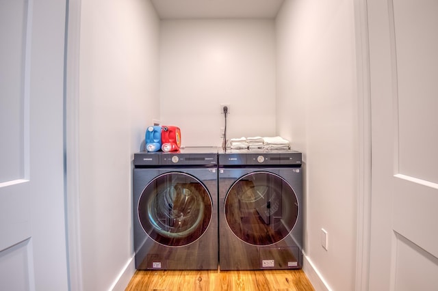 washroom featuring laundry area, washing machine and dryer, baseboards, and wood finished floors