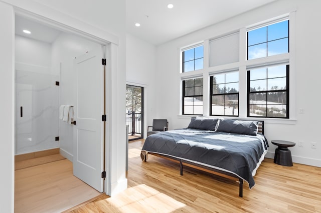 bedroom featuring access to exterior, multiple windows, wood finished floors, and baseboards