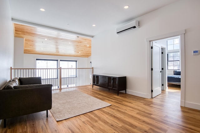 living area featuring recessed lighting, an AC wall unit, baseboards, and wood finished floors