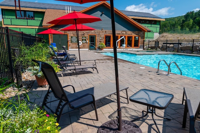 community pool featuring a patio area, fence, and a hot tub