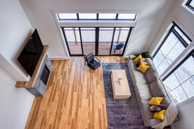 unfurnished living room with a fireplace with flush hearth, a towering ceiling, and wood finished floors