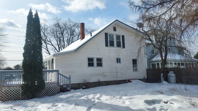 snow covered back of property featuring a wooden deck