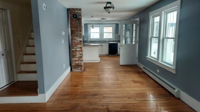 interior space featuring a baseboard heating unit, stairway, light wood-style floors, and a sink