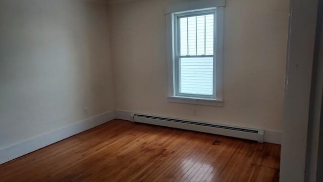 spare room featuring baseboard heating, baseboards, and wood finished floors