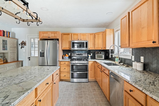 kitchen featuring a sink, appliances with stainless steel finishes, light tile patterned flooring, decorative backsplash, and light stone countertops