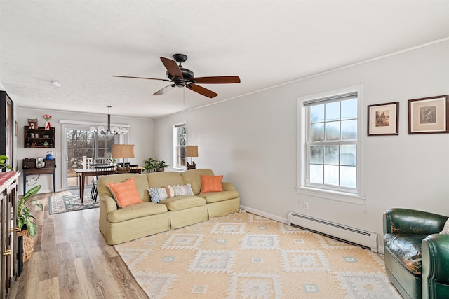 living room featuring baseboards, ornamental molding, baseboard heating, ceiling fan with notable chandelier, and wood finished floors