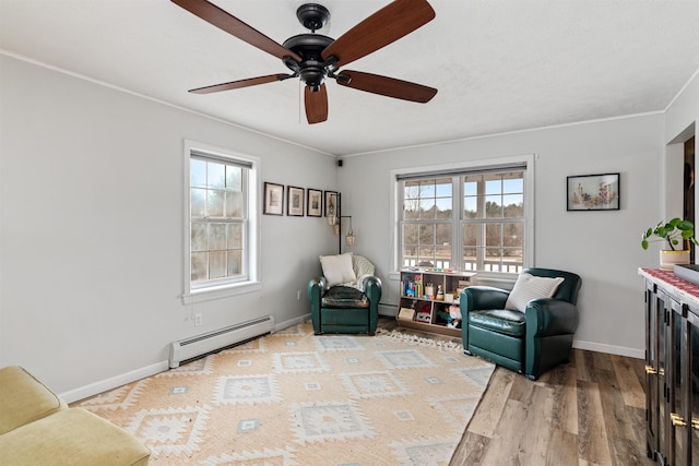 sitting room featuring baseboards, a baseboard radiator, light wood-style flooring, ceiling fan, and crown molding