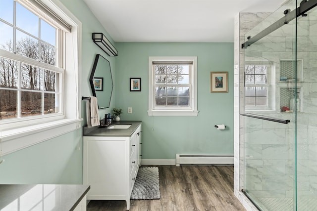 bathroom featuring a healthy amount of sunlight, a stall shower, and a baseboard heating unit