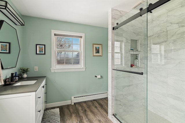 full bath featuring a stall shower, wood finished floors, vanity, and a baseboard radiator