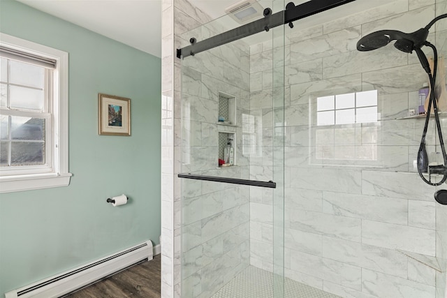 bathroom featuring wood finished floors, baseboard heating, and a stall shower