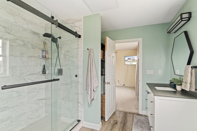 full bath featuring a shower stall, vanity, baseboards, and wood finished floors